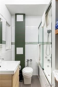 full bathroom featuring toilet, bath / shower combo with glass door, and vanity