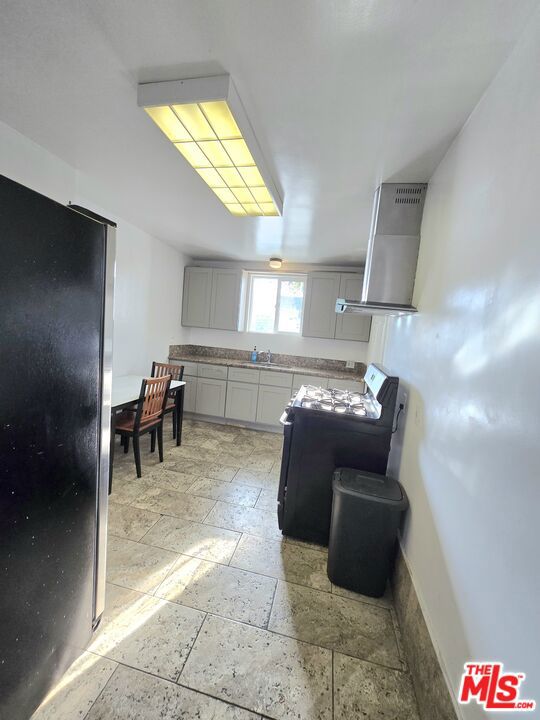 kitchen with range, sink, stainless steel fridge, gray cabinets, and range hood