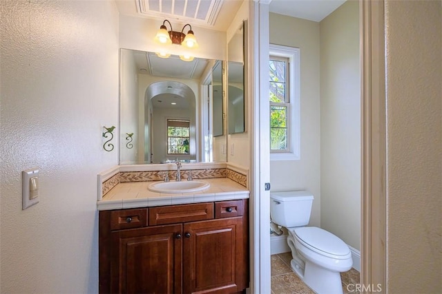 bathroom with toilet, vanity, and tile patterned flooring