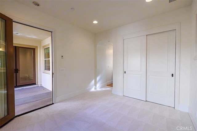 unfurnished bedroom featuring light carpet and a closet