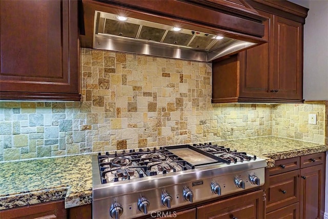 kitchen with stainless steel gas stovetop, light stone countertops, tasteful backsplash, and custom range hood