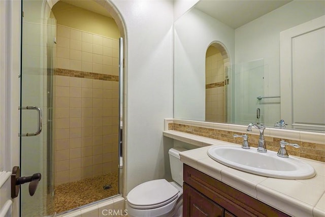 bathroom featuring decorative backsplash, toilet, walk in shower, and vanity