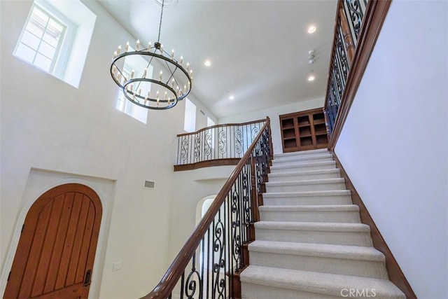 stairs with a high ceiling and an inviting chandelier