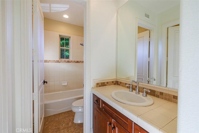 full bathroom featuring toilet, vanity, tile patterned flooring, tiled shower / bath, and decorative backsplash