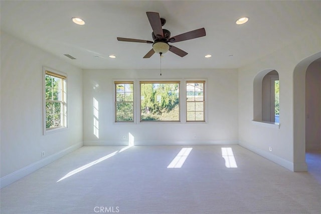 empty room featuring ceiling fan, plenty of natural light, and light carpet