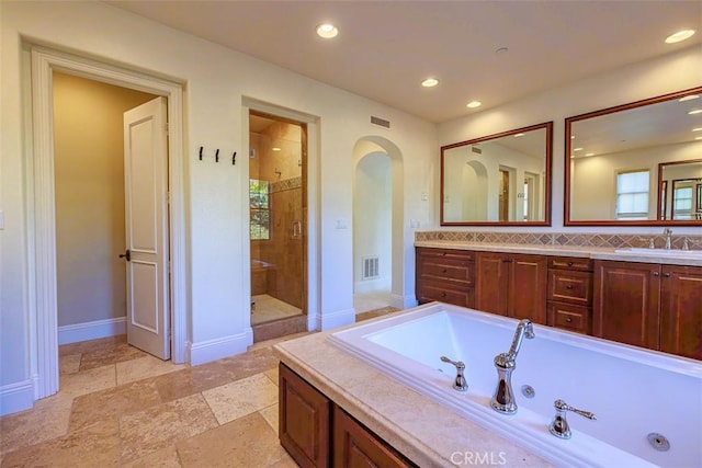 bathroom featuring tasteful backsplash, vanity, and plus walk in shower