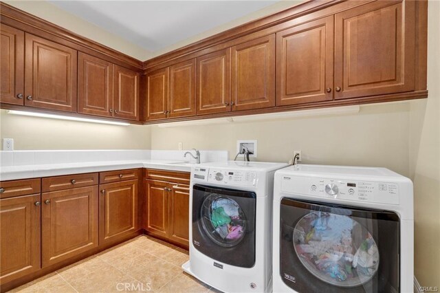 clothes washing area with light tile patterned floors, cabinets, washer and clothes dryer, and sink