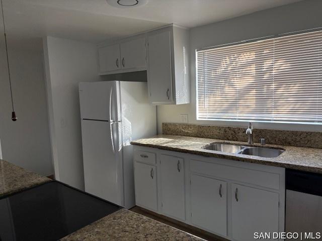 kitchen with white cabinets, sink, and white fridge