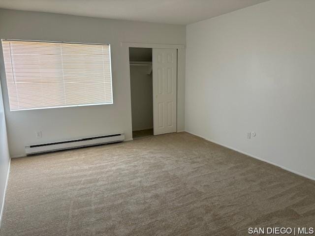 unfurnished bedroom featuring baseboard heating, carpet, and a closet