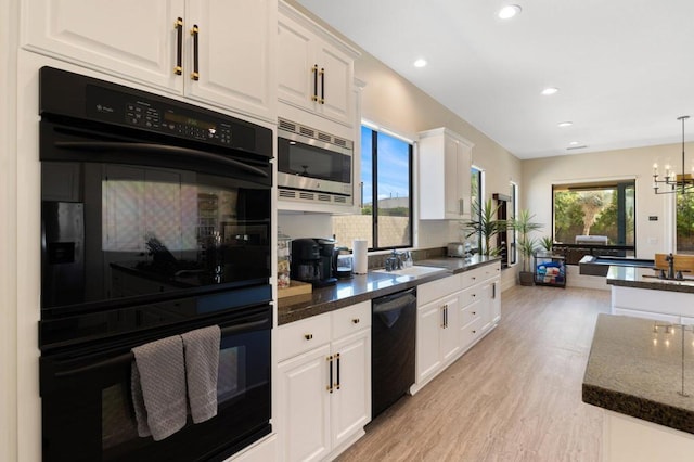 kitchen with light hardwood / wood-style floors, pendant lighting, white cabinets, and black appliances