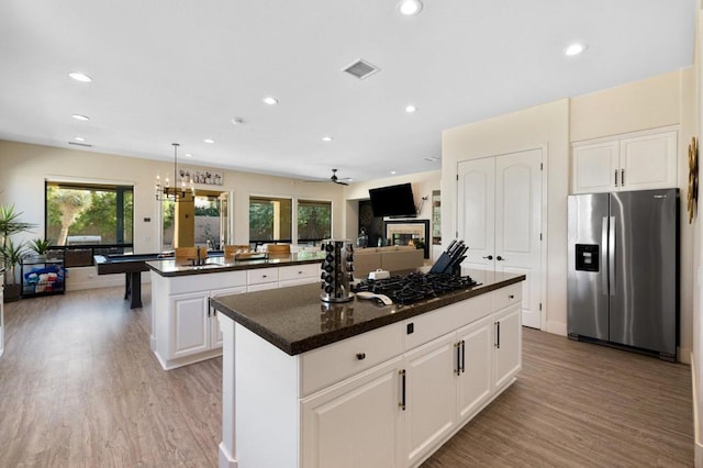 kitchen featuring decorative light fixtures, a kitchen island, light hardwood / wood-style flooring, stainless steel appliances, and white cabinets