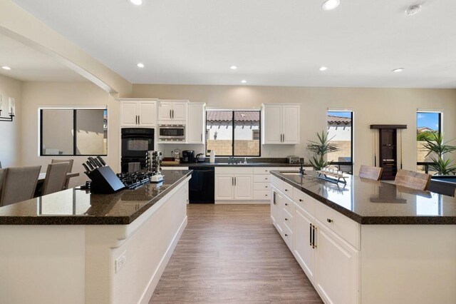 kitchen with white cabinets, a spacious island, and black appliances