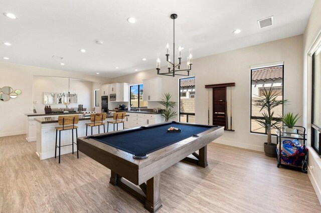 rec room with pool table, a chandelier, and light wood-type flooring