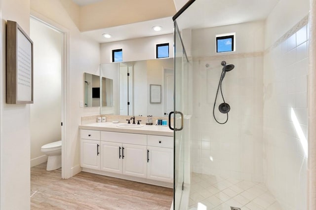 bathroom featuring hardwood / wood-style flooring, toilet, vanity, and walk in shower