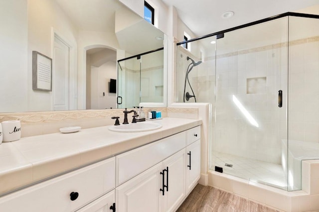 bathroom featuring wood-type flooring, walk in shower, and vanity