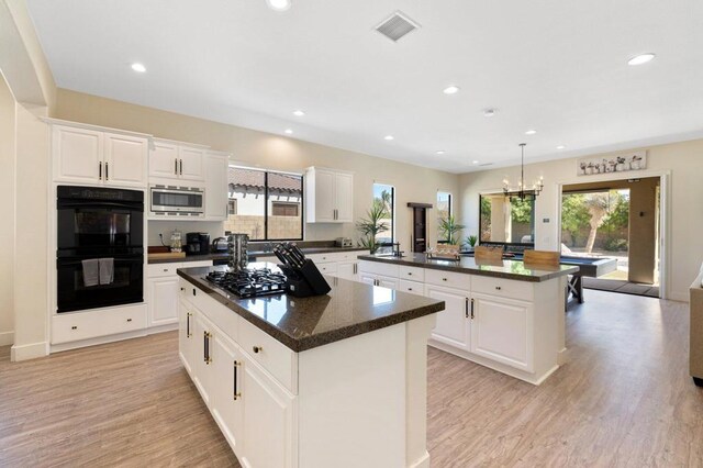 kitchen featuring a kitchen island, stainless steel appliances, white cabinetry, and decorative light fixtures