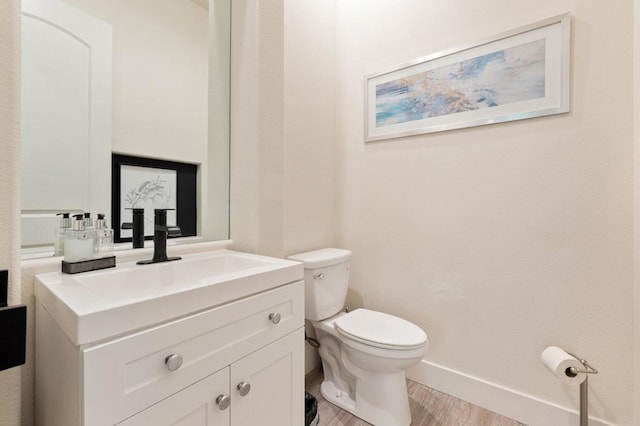 bathroom with hardwood / wood-style flooring, toilet, and vanity