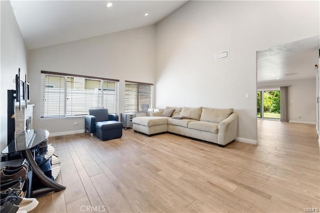 living room with light hardwood / wood-style floors and high vaulted ceiling