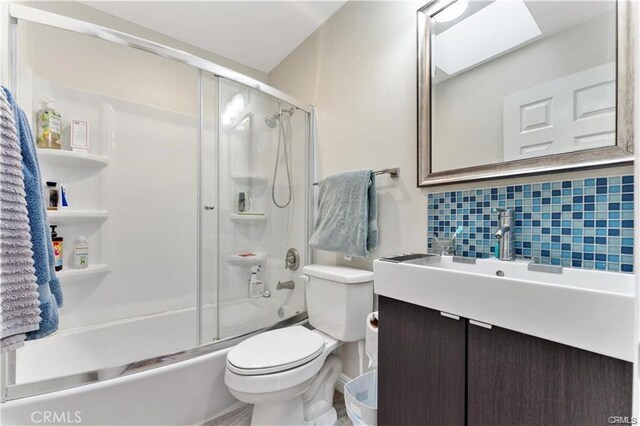 full bathroom with toilet, vanity, backsplash, and shower / bath combination with glass door