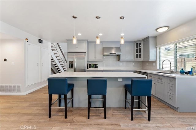 kitchen featuring decorative light fixtures, stainless steel appliances, exhaust hood, and a kitchen island