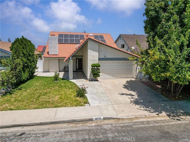 view of front property featuring a garage, a front yard, and solar panels