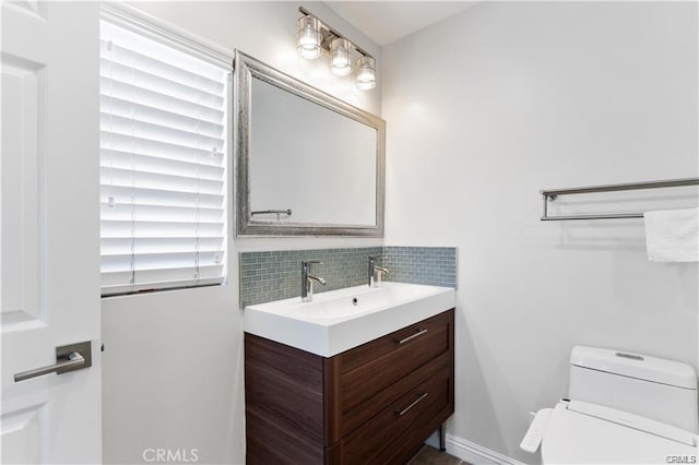 bathroom featuring toilet, vanity, and decorative backsplash