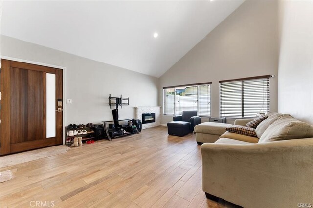 living room with high vaulted ceiling, light wood-type flooring, and a fireplace