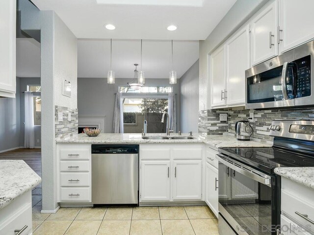 kitchen with appliances with stainless steel finishes, white cabinetry, tasteful backsplash, and sink