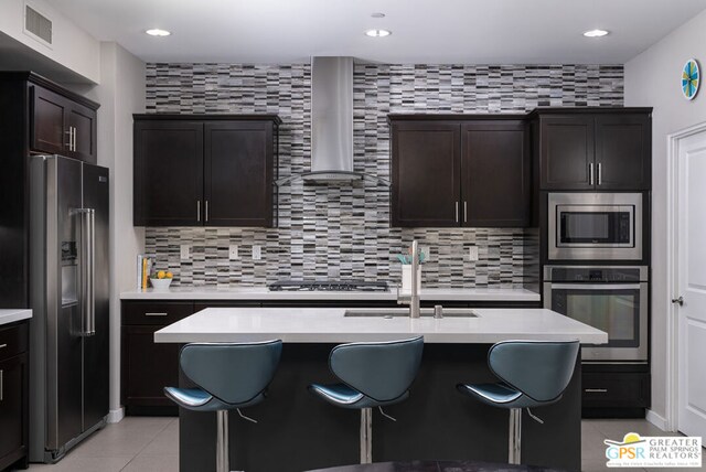 kitchen featuring decorative backsplash, appliances with stainless steel finishes, sink, and wall chimney exhaust hood