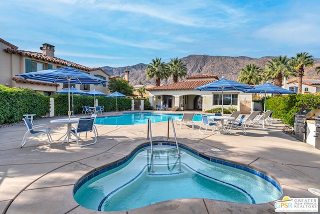 view of swimming pool featuring a hot tub, a patio area, a mountain view, and area for grilling