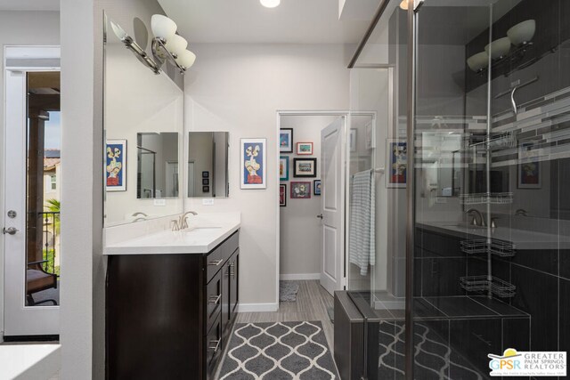 bathroom featuring a shower with shower door and vanity