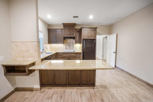 kitchen featuring backsplash, black appliances, kitchen peninsula, and light hardwood / wood-style flooring