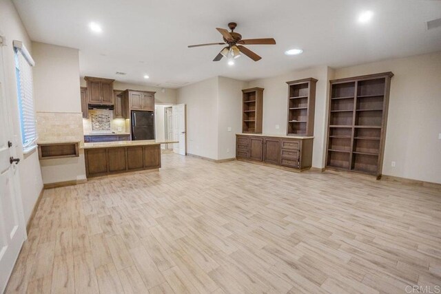 kitchen featuring black refrigerator, light hardwood / wood-style floors, backsplash, kitchen peninsula, and ceiling fan