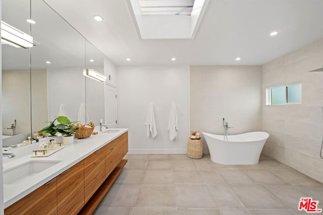 bathroom featuring vanity, a bath, and a skylight