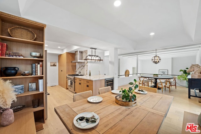 dining area with a chandelier, beverage cooler, and light hardwood / wood-style floors