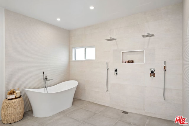 bathroom featuring tile patterned flooring, plus walk in shower, and tile walls