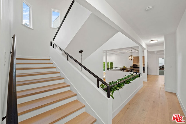 stairway with a notable chandelier and hardwood / wood-style flooring