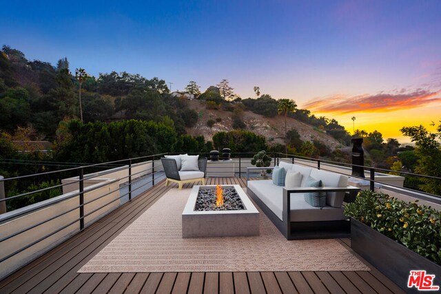 deck at dusk featuring an outdoor living space with a fire pit