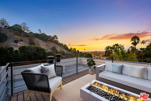 deck at dusk with an outdoor living space with a fire pit