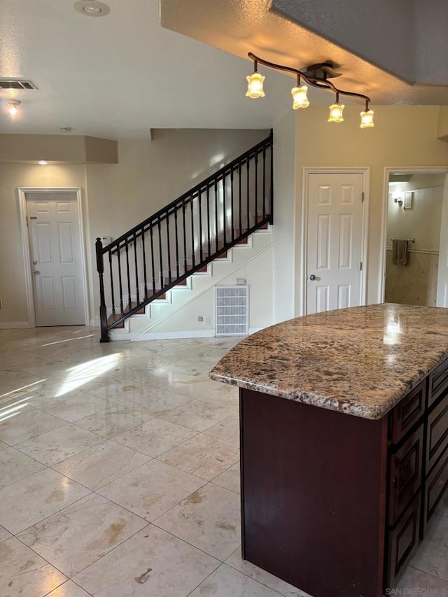 kitchen featuring light stone counters, pendant lighting, dark brown cabinets, and a textured ceiling