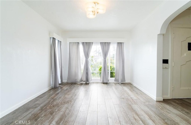 spare room featuring light hardwood / wood-style floors and a notable chandelier