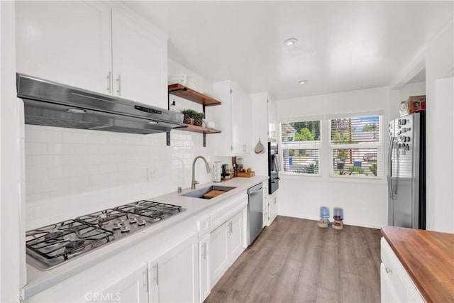 kitchen featuring wood counters, appliances with stainless steel finishes, tasteful backsplash, white cabinets, and sink