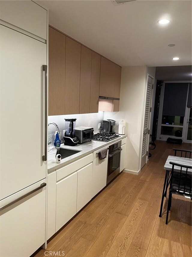 kitchen featuring appliances with stainless steel finishes, sink, and light hardwood / wood-style flooring