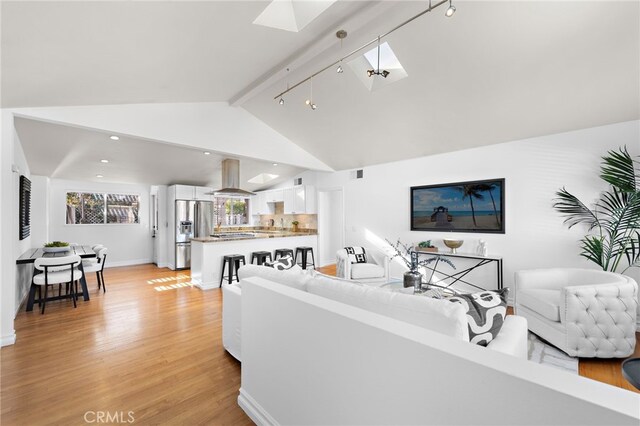 living room with light hardwood / wood-style flooring and lofted ceiling with skylight