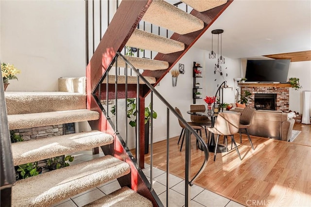 stairs with a brick fireplace and hardwood / wood-style floors