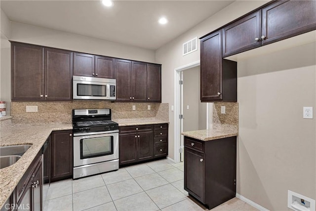 kitchen with appliances with stainless steel finishes, tasteful backsplash, dark brown cabinetry, and light stone countertops