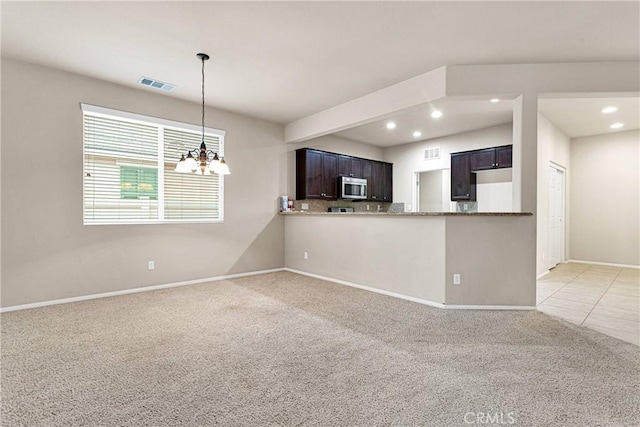 kitchen with backsplash, a notable chandelier, kitchen peninsula, dark brown cabinetry, and light carpet