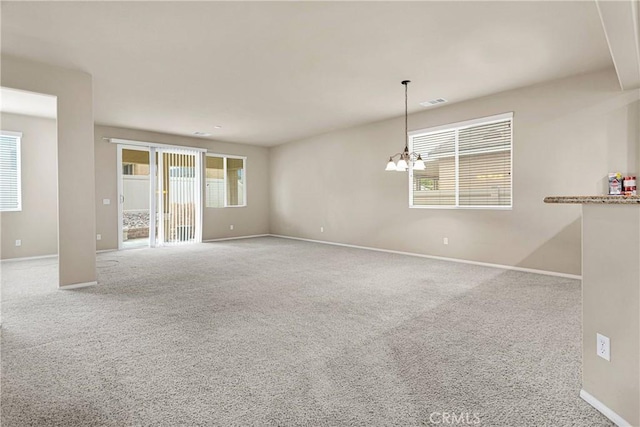 carpeted empty room featuring a notable chandelier