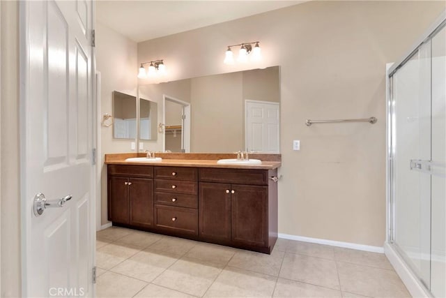 bathroom featuring tile patterned flooring, a shower with shower door, and vanity