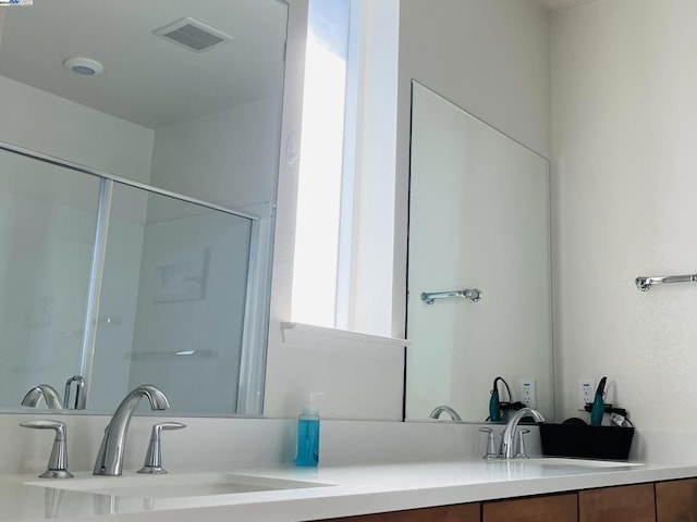 bathroom with a shower with shower door and vanity